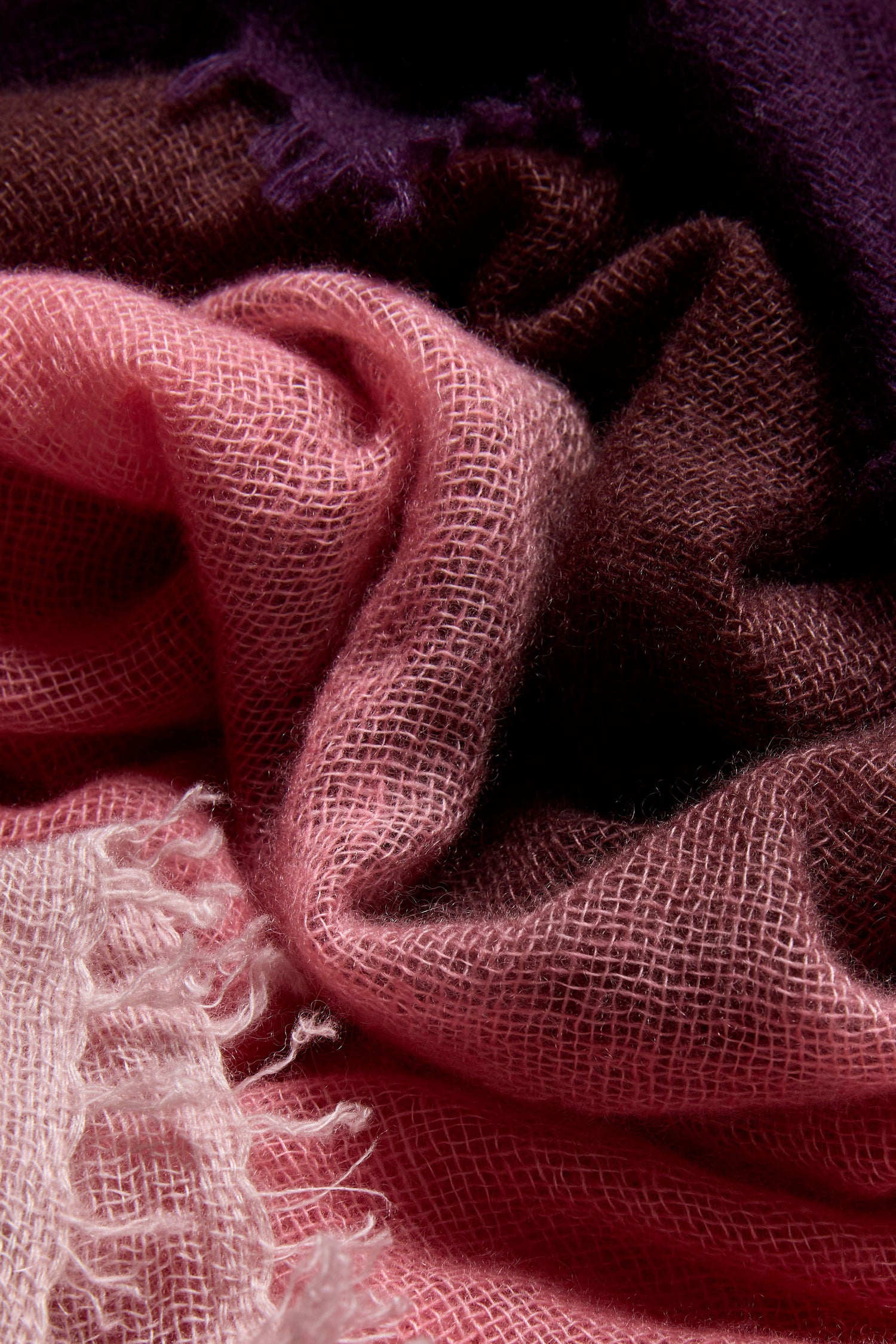 Close-up of the Cherry and Pink Soft Colourblend Cashmere Shawl, featuring loosely woven ombré cashmere in shades of pink, brown, and dark purple, with visible texture and fringe on one edge—a luxurious shawl crafted in Nepal.