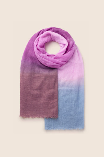 The St Tropez Cashmere Shawl is a luxurious piece featuring a gradient watercolour design that flows seamlessly from deep purple to lavender to light blue, crafted from soft and lightweight fabric.