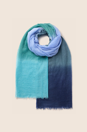 A St Tropez Cashmere Shawl, transitioning from light blue to dark blue, draped in a loop.