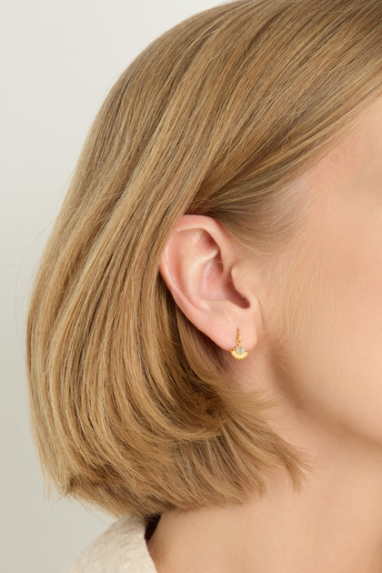 Close-up of a person's left ear wearing a Gold Plated Labradorite Sunburst Earring; person has short, straight blonde hair.