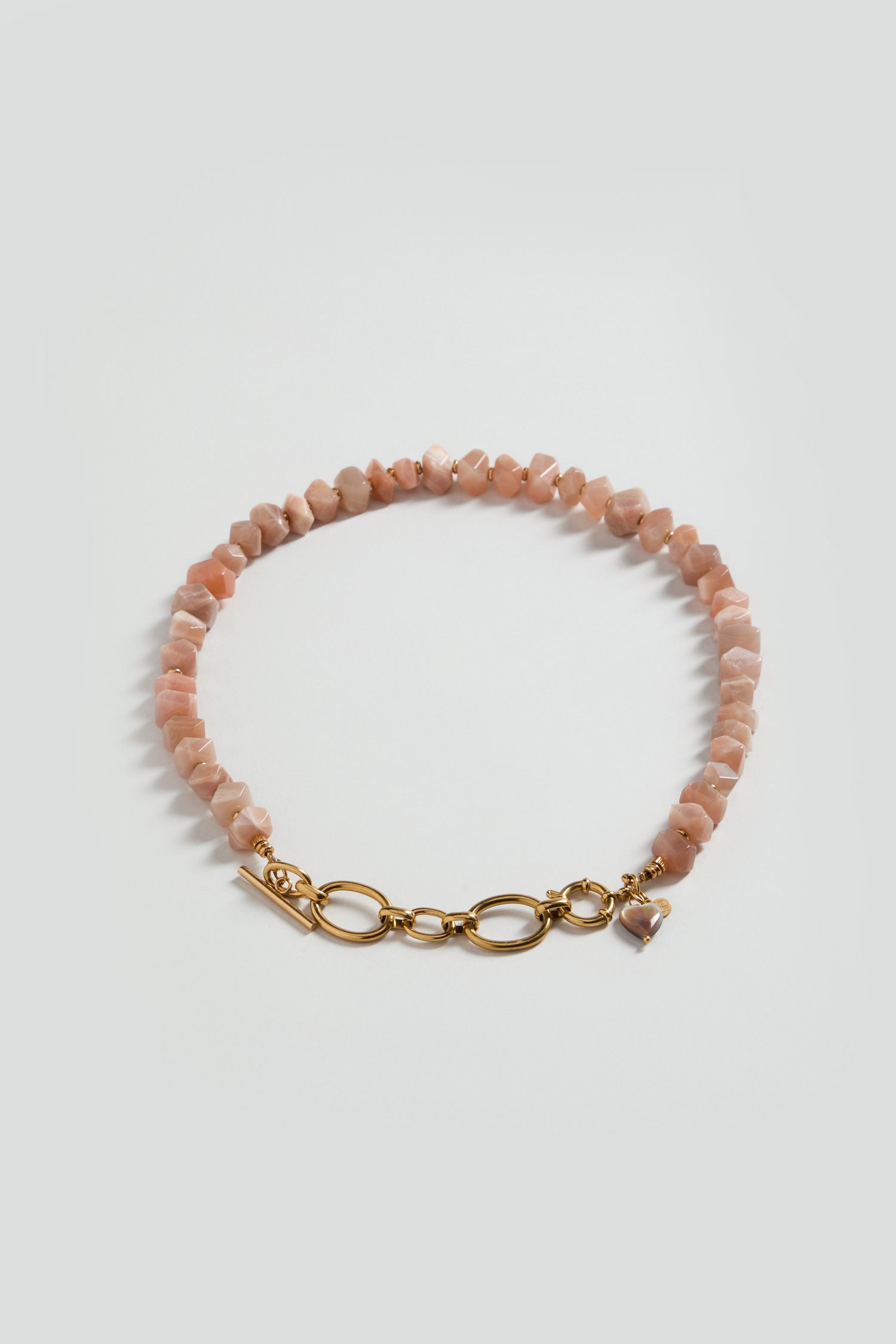 The Amazonite Bead Necklace features pinkish irregular beads with a blue-green amazonite gemstone accent and a gold toggle clasp, displayed on a plain light background.