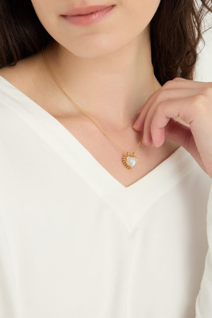 A person in a white top showcases the Gold Plated White Moonstone Heart Necklace, featuring an elegant heart-shaped pendant.