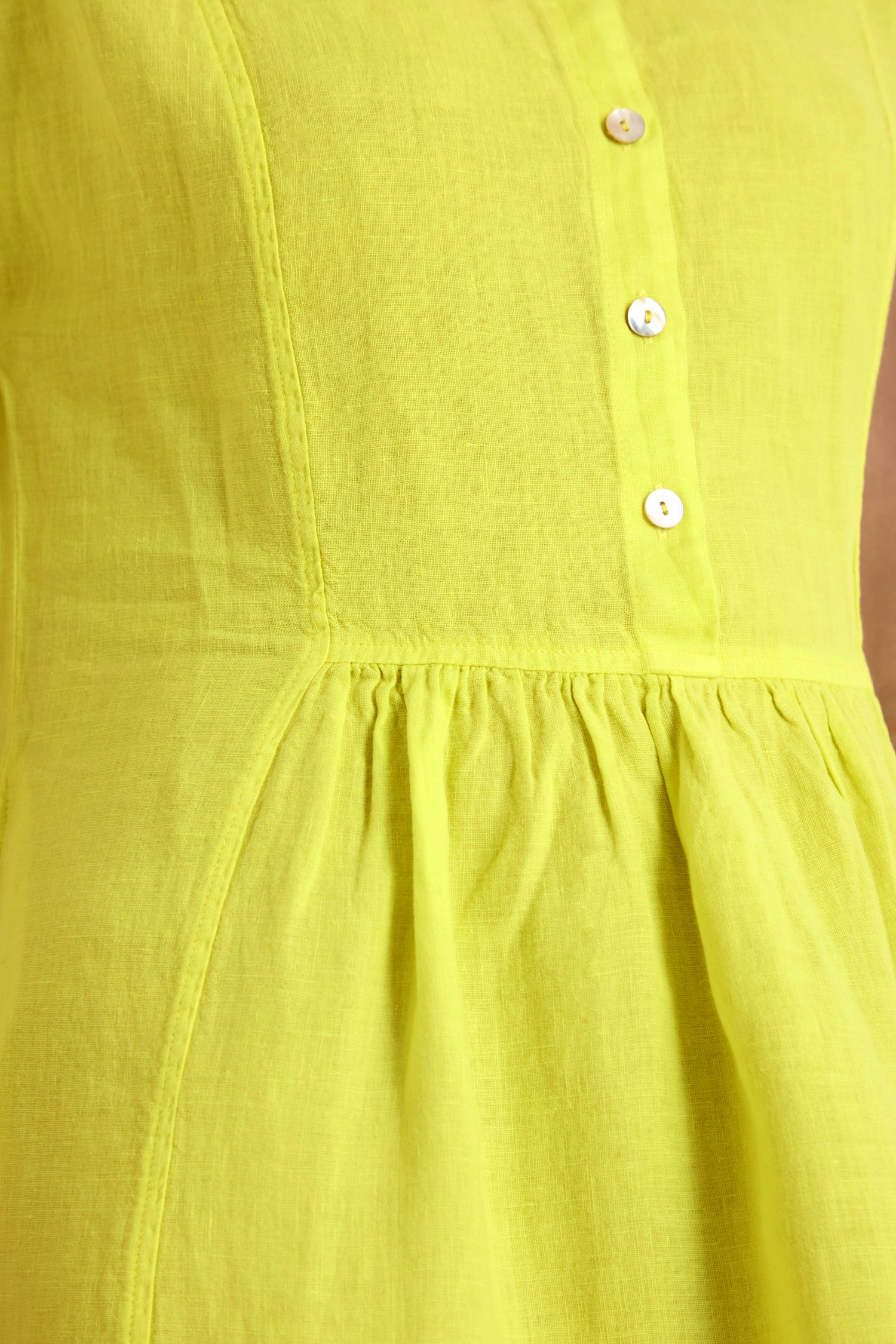 Close-up of the Linen Button Lemon Placket Dress, featuring white buttons, a gathered waist, and a flattering fit-and-flare midi silhouette.