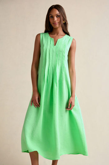 A woman faces forward, wearing the Linen Pleat Front Sleeveless Dress in mint green, a loose-fitting summer staple with pleat front details, set against a plain beige background.