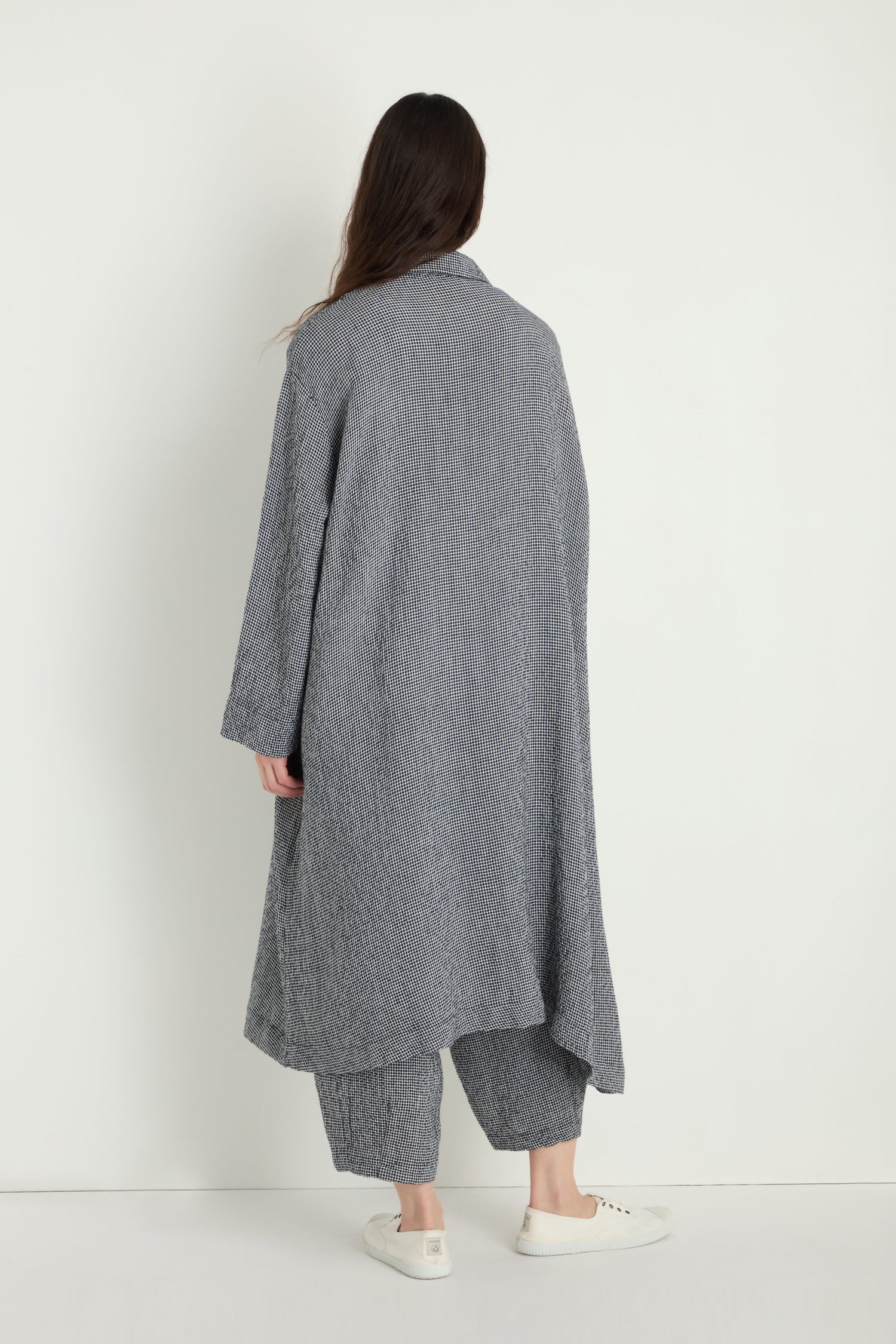 A person stands with their back to the camera against a white background, wearing the Micro Gingham Boxy Coat with matching loose pants and white sneakers.