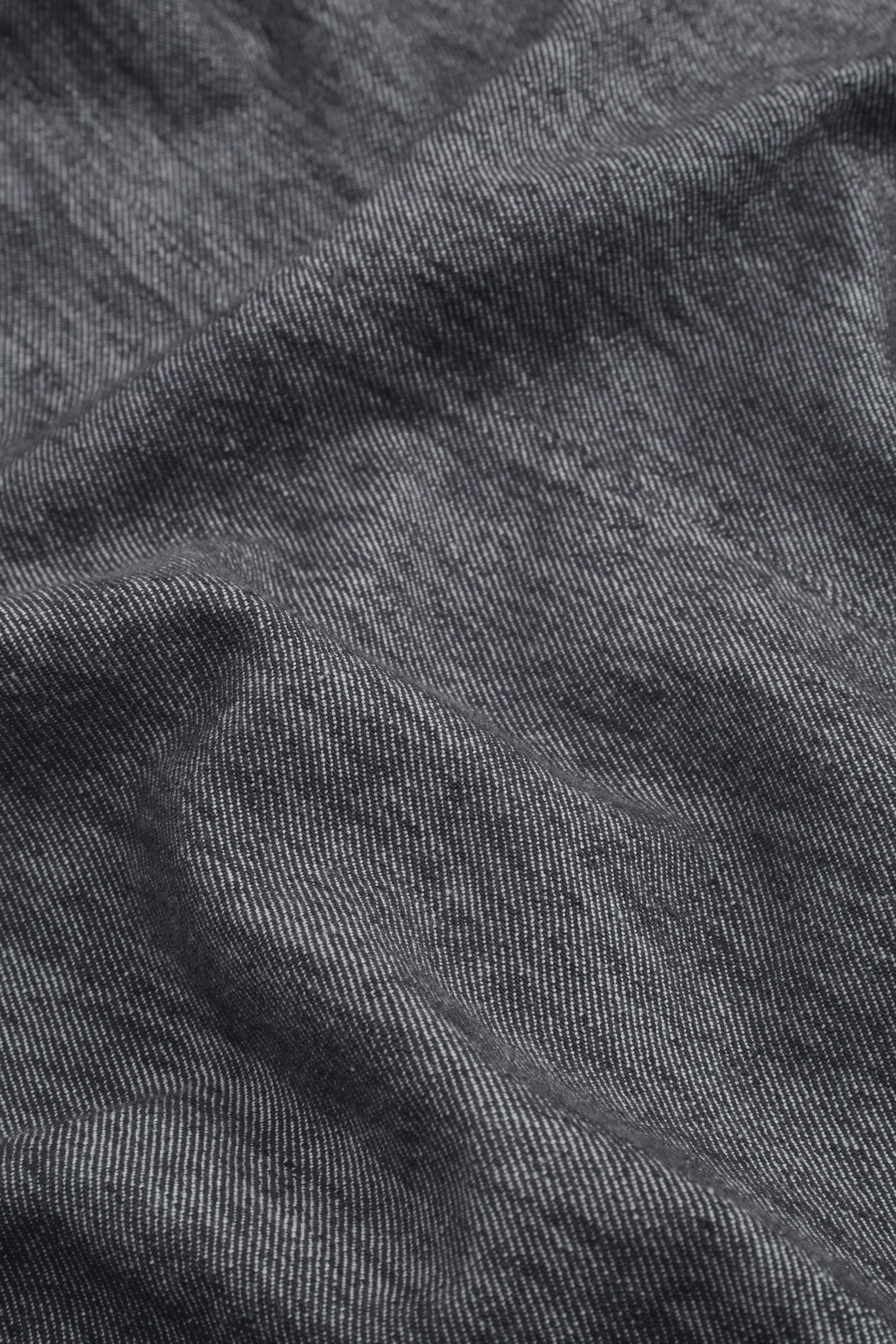 Close-up of dark gray, slightly wrinkled fabric from the Washed Cotton Linen Jacket, featuring fine white vertical lines and a visible texture reminiscent of classic washed denim.