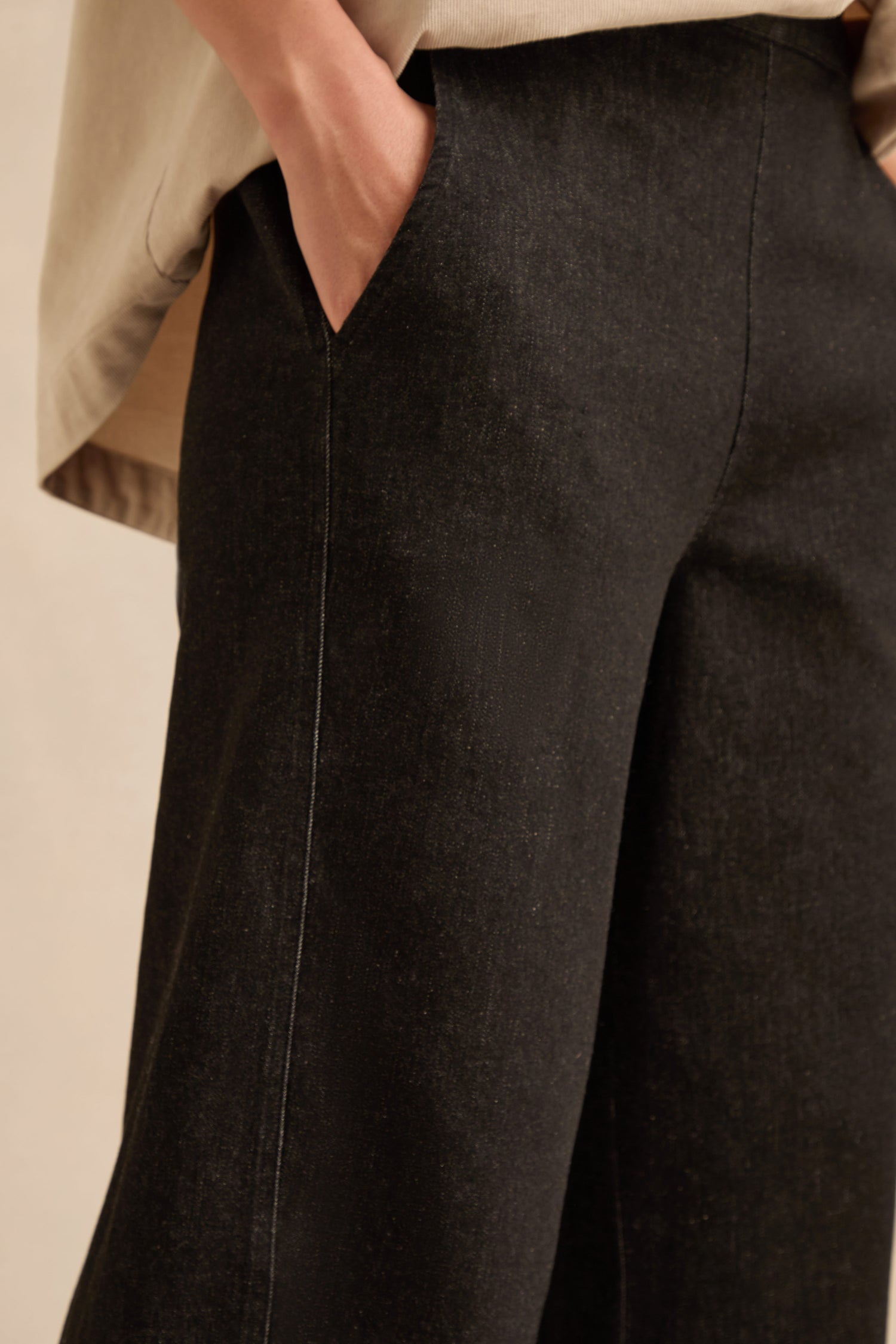 A person wearing Stretch Black Denim Bubble Trousers with one hand in the pocket, shown from waist to mid-thigh.