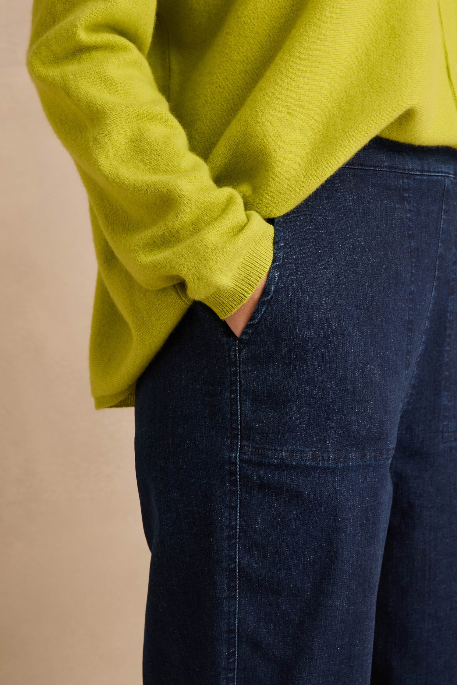 A person wearing a bright yellow sweater and Stretch Denim Blue Straight Trousers stands with one hand in their pocket against a neutral background.