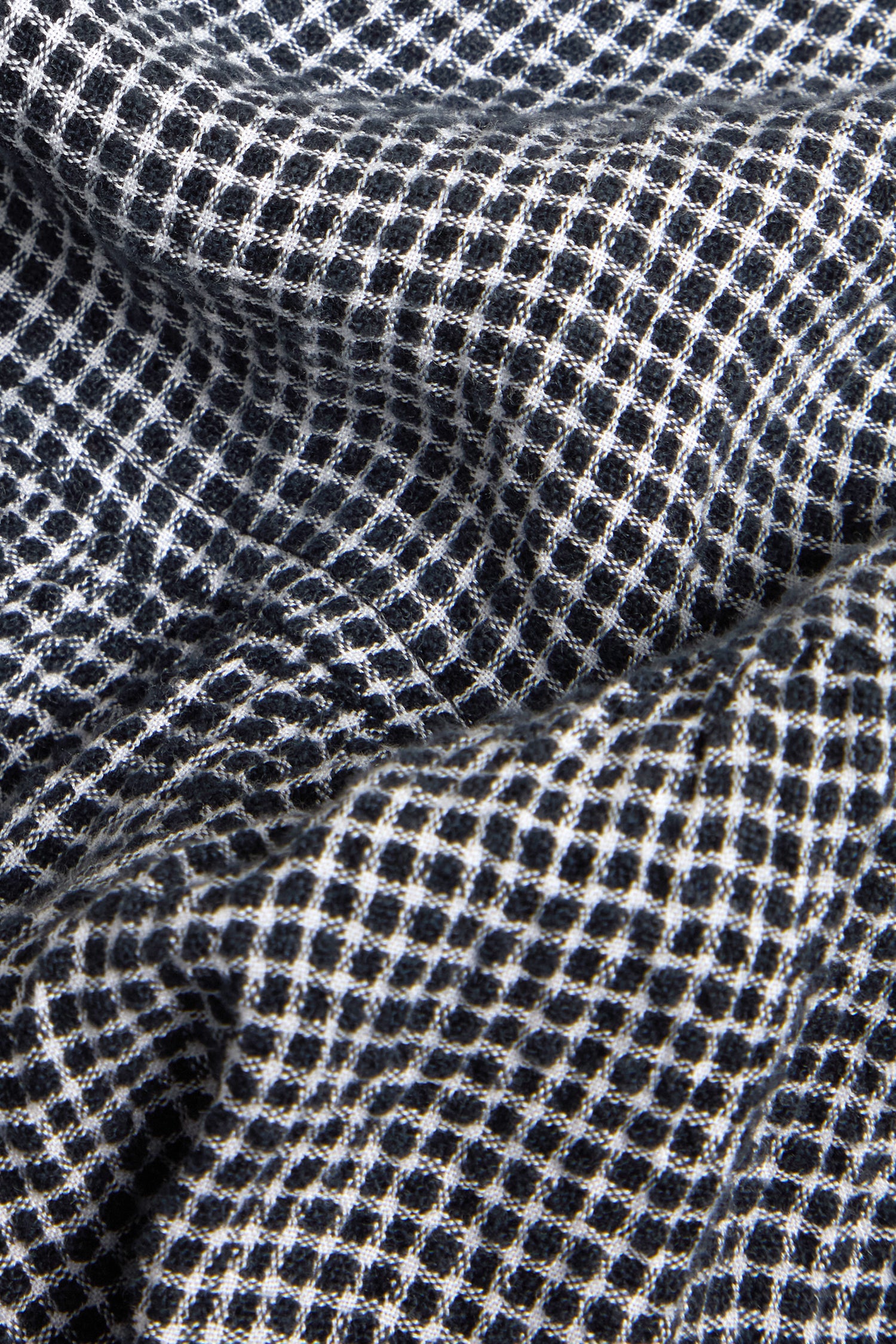 Close-up of Micro Gingham Bubble Trouser fabric, showing its black and white small checkered pattern and textured surface.