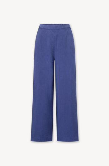 A women's Soft Tencel Wide Trouser in a dark blue color. Made with TENCEL LYOCELL fabric, it features an elasticated waistband for comfort and wide trousers for a stylish fit.