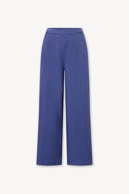A women's Soft Tencel Wide Trouser in a dark blue color. Made with TENCEL LYOCELL fabric, it features an elasticated waistband for comfort and wide trousers for a stylish fit.
