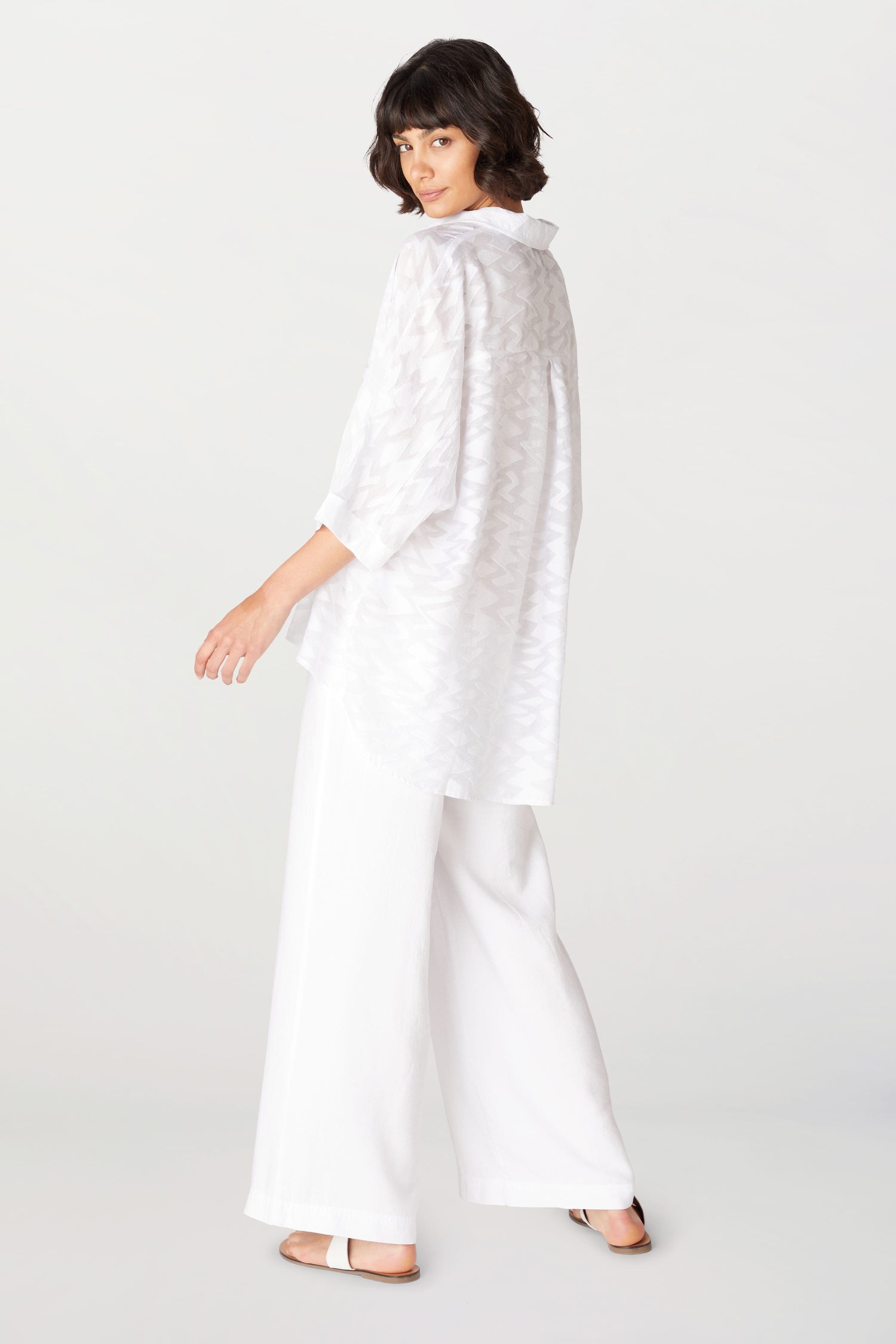 The back view of a woman wearing a white blouse and Soft Tencel Wide Trouser.