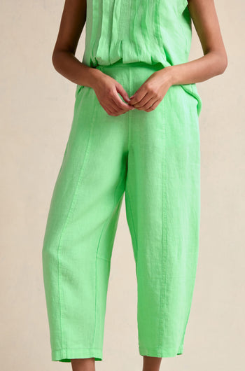 A person stands against a plain background, hands clasped at the waist, wearing Linen Seam Detail Pistachio Bubble Trouser featuring an elasticated waistband and a sleeveless matching light green top.