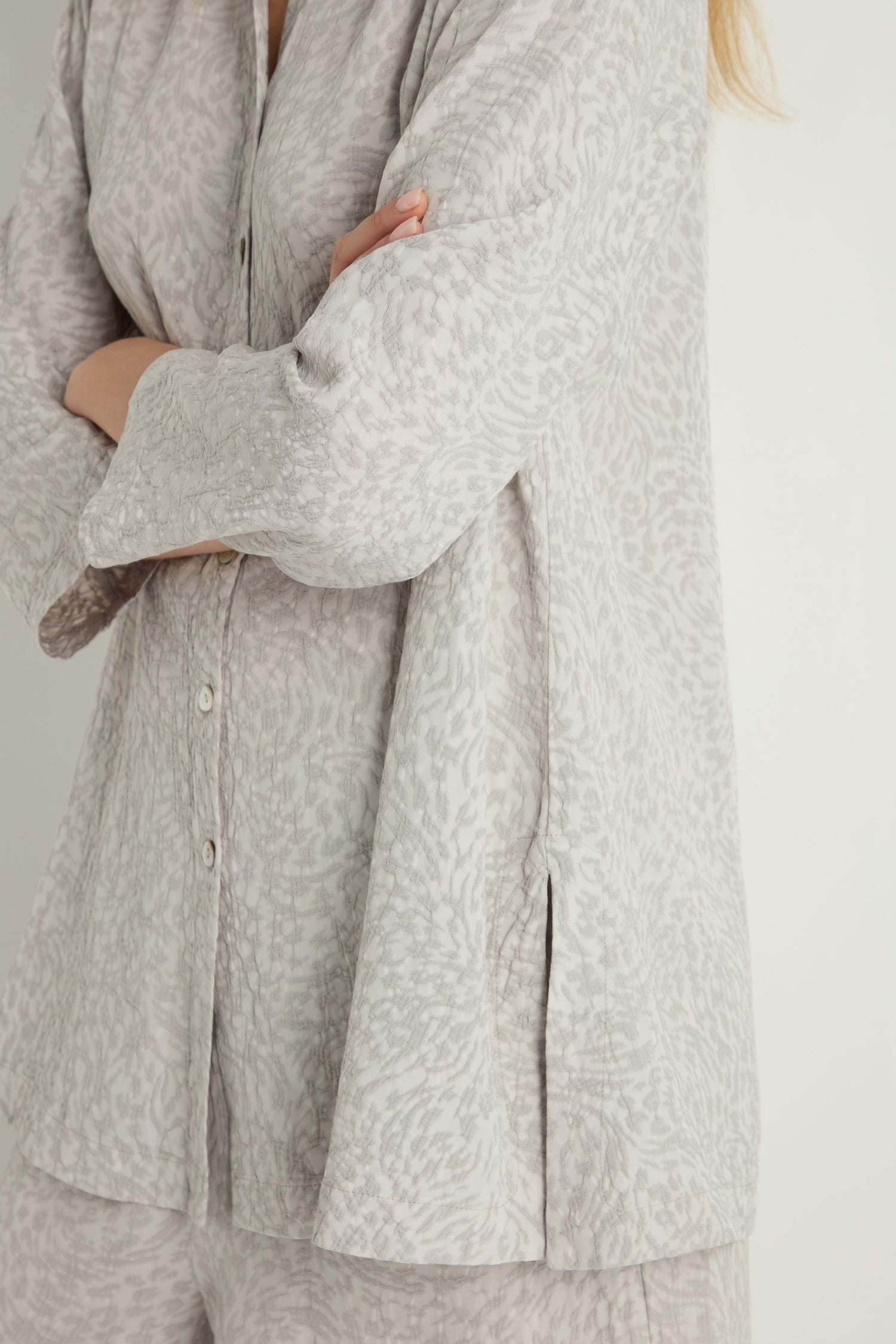Person in a light gray Animal Textured Jacquard Nehru Shirt and matching pants, arms crossed and facing away from the camera.