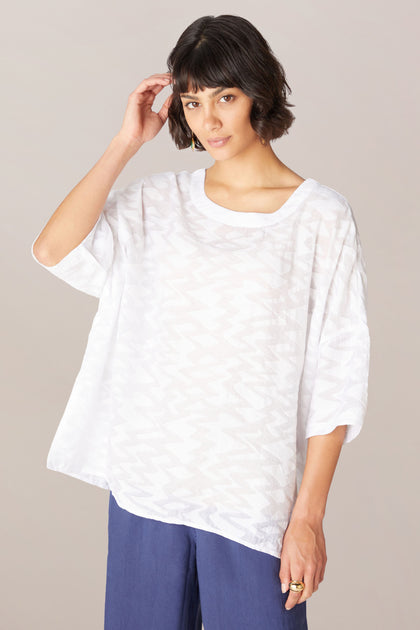 A woman wearing a Zig Zag Jacquard Top and blue pants in a relaxed boxy fit.