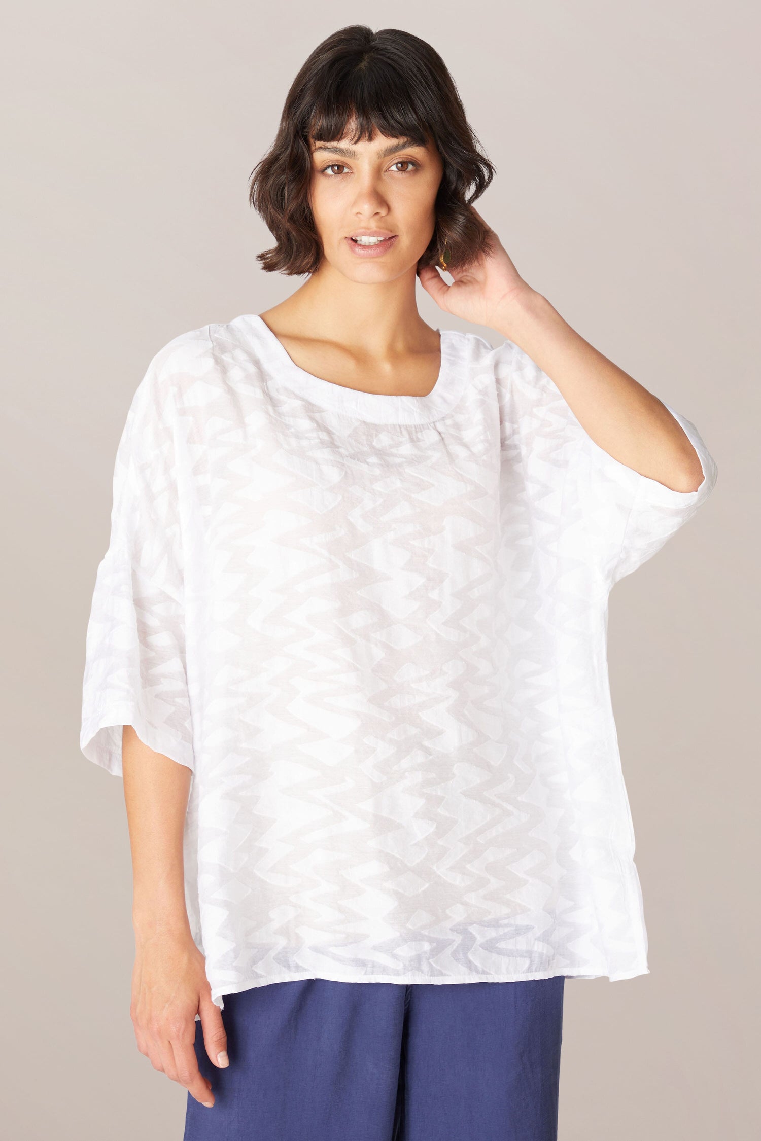 A woman wearing a relaxed boxy fit Zig Zag Jacquard top and blue pants made of a viscose blend fabric.