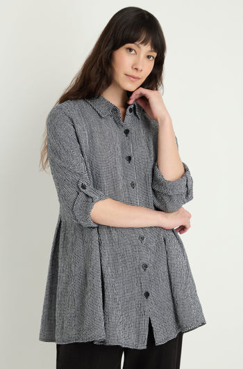 A woman stands against a light background wearing a long-sleeved Micro Gingham Shirt, featuring rolled sleeves and crafted from a linen-viscose blend.
