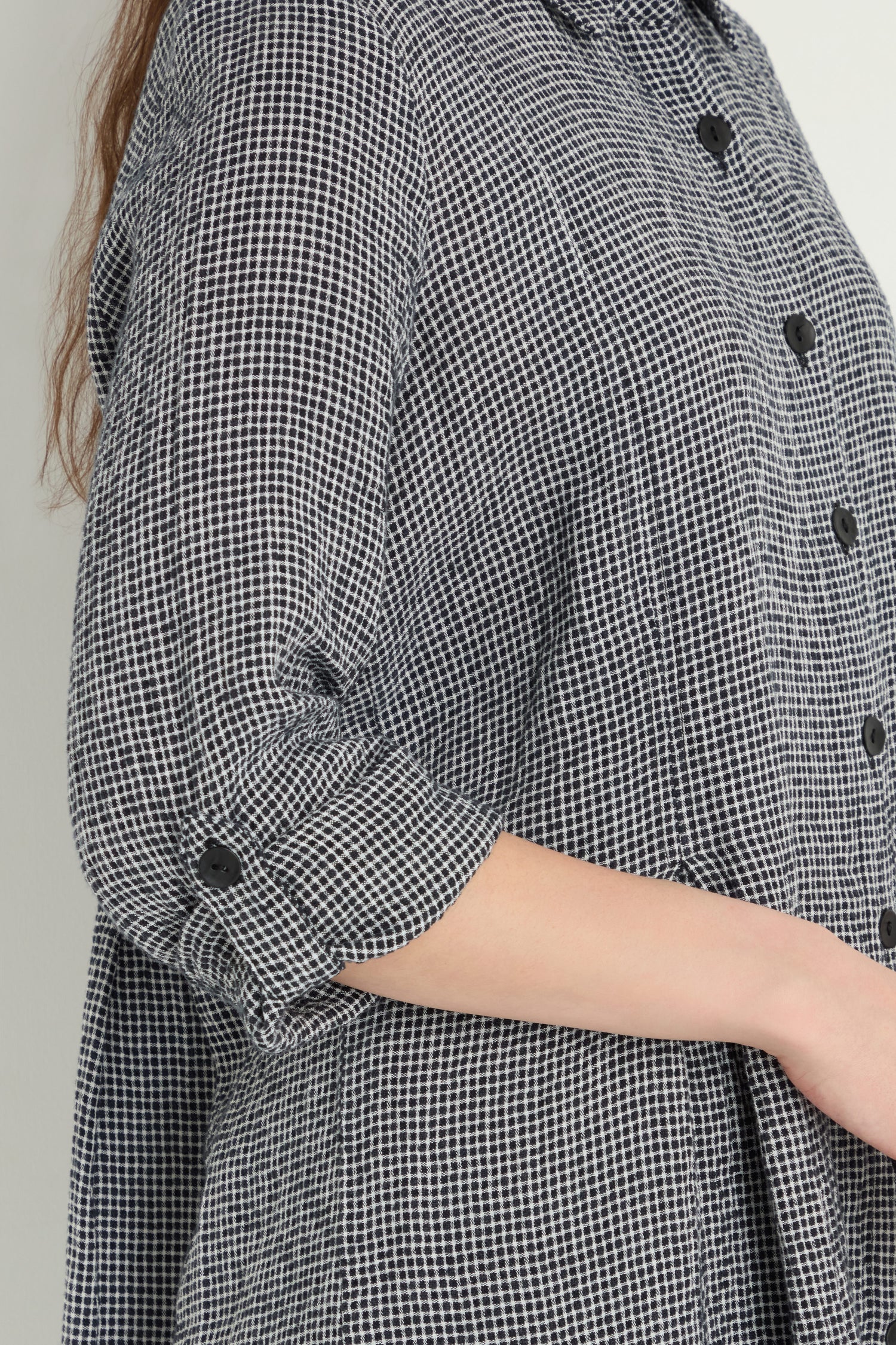 Someone is wearing the Micro Gingham Shirt, a long-sleeve, black and white shirt with sleeves partially rolled up.