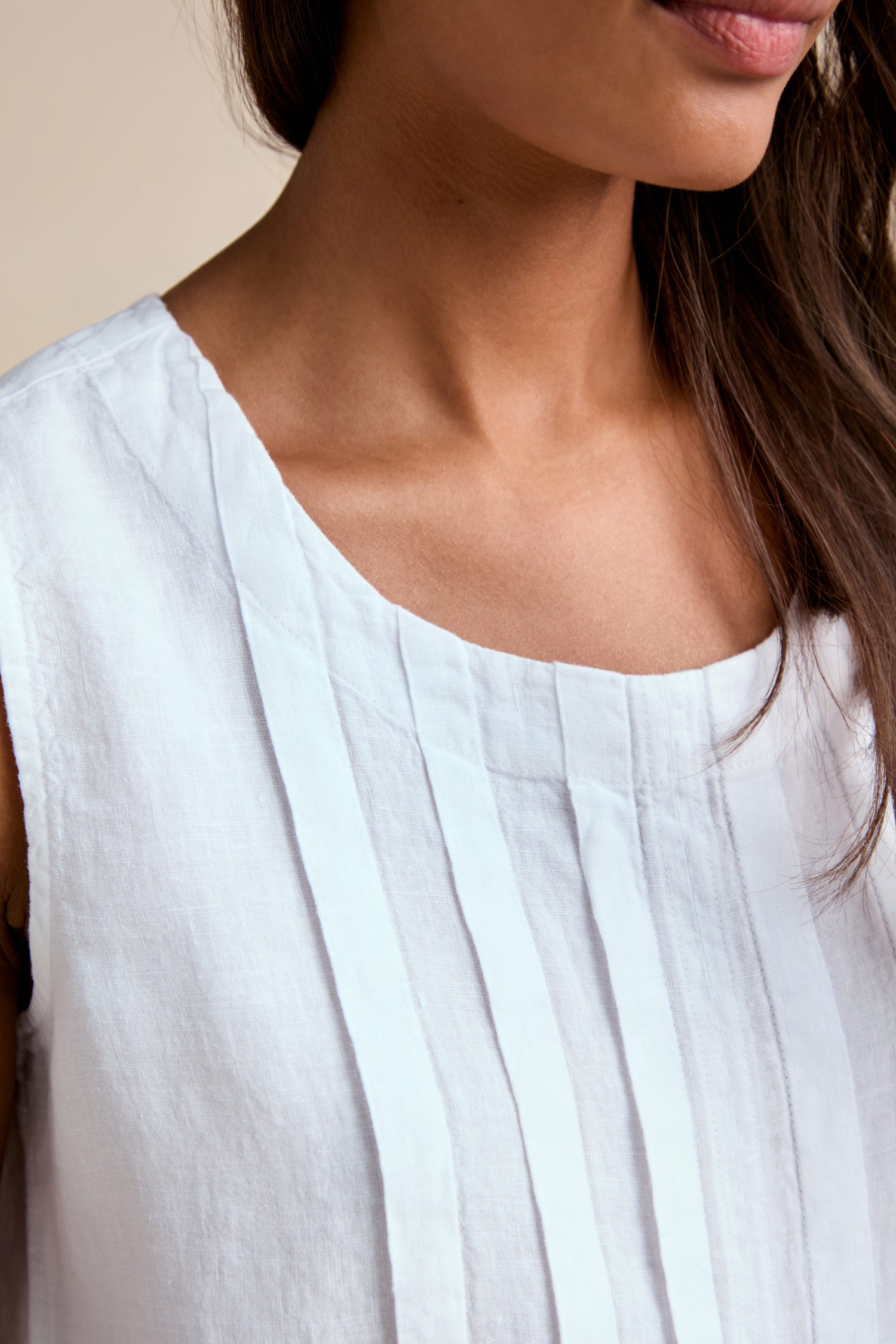 A close-up of a person wearing the Linen Pleat Front White Vest, highlighting the sleeveless design, pleat front detail, and showing their neck, shoulder, and part of their face.
