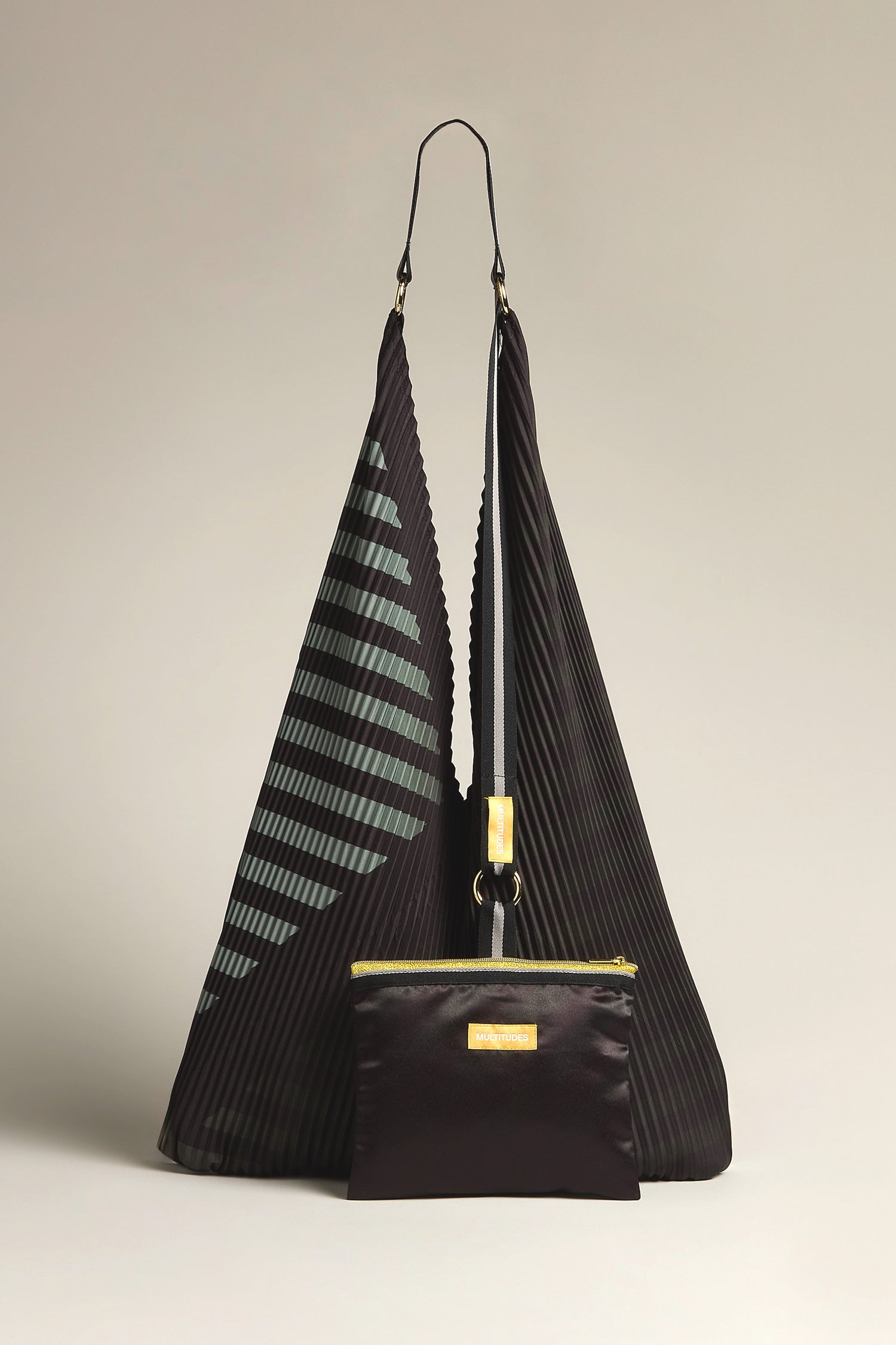 The Pleated Y Handbag features a black design with geometric patterns, crafted sustainably, and includes a front zippered pouch on a neutral backdrop.