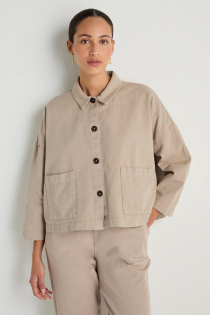 A woman wearing the Heavy Cotton Boxy Jacket in beige with large front pockets and matching beige pants stands against a plain white background.