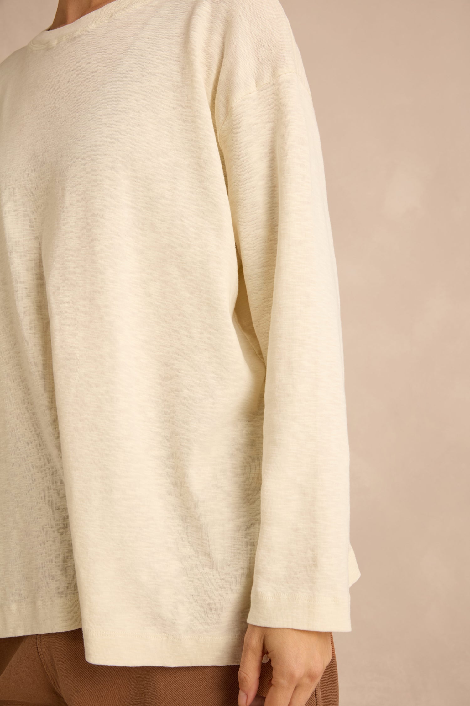 A person wearing the Cream Boxy Cotton Jersey T Shirt and brown pants, shown from the shoulders to the hips against a neutral background.