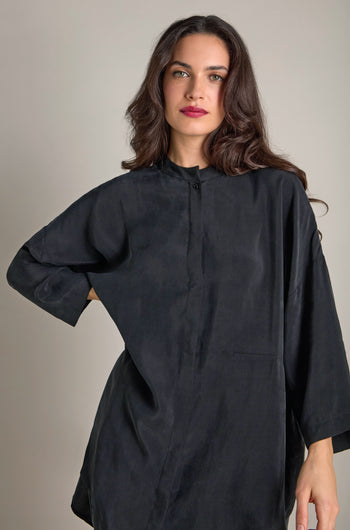 A woman wearing the Elba One Pocket Easy Cupro Shirt with a drop shoulder design stands against a neutral background.