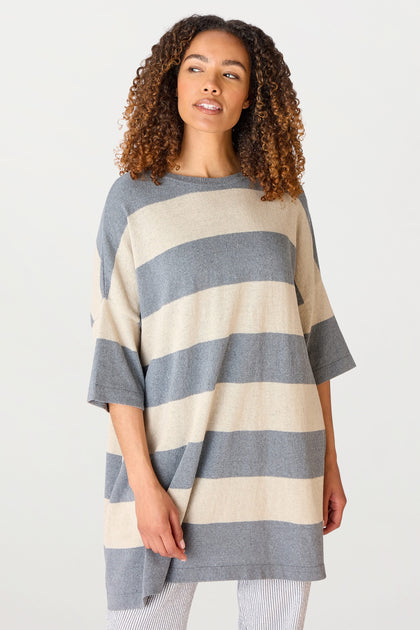 A woman with curly hair wearing a Vera Stripe Top stands against a plain background.