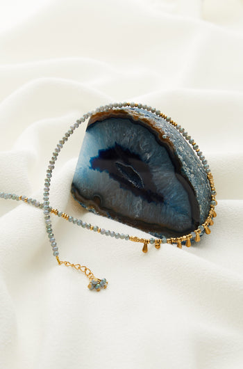 A Matit Necklace with a blue agate and gold beads.