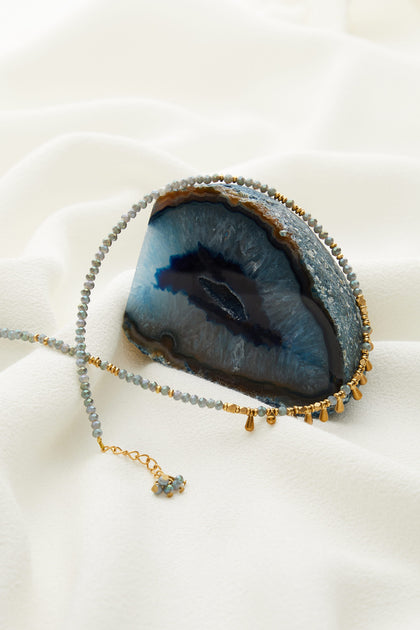 A Matit Necklace with a blue agate and gold beads.