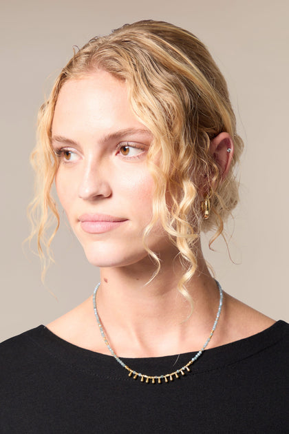 A woman with curly hair wearing a Matit Necklace.