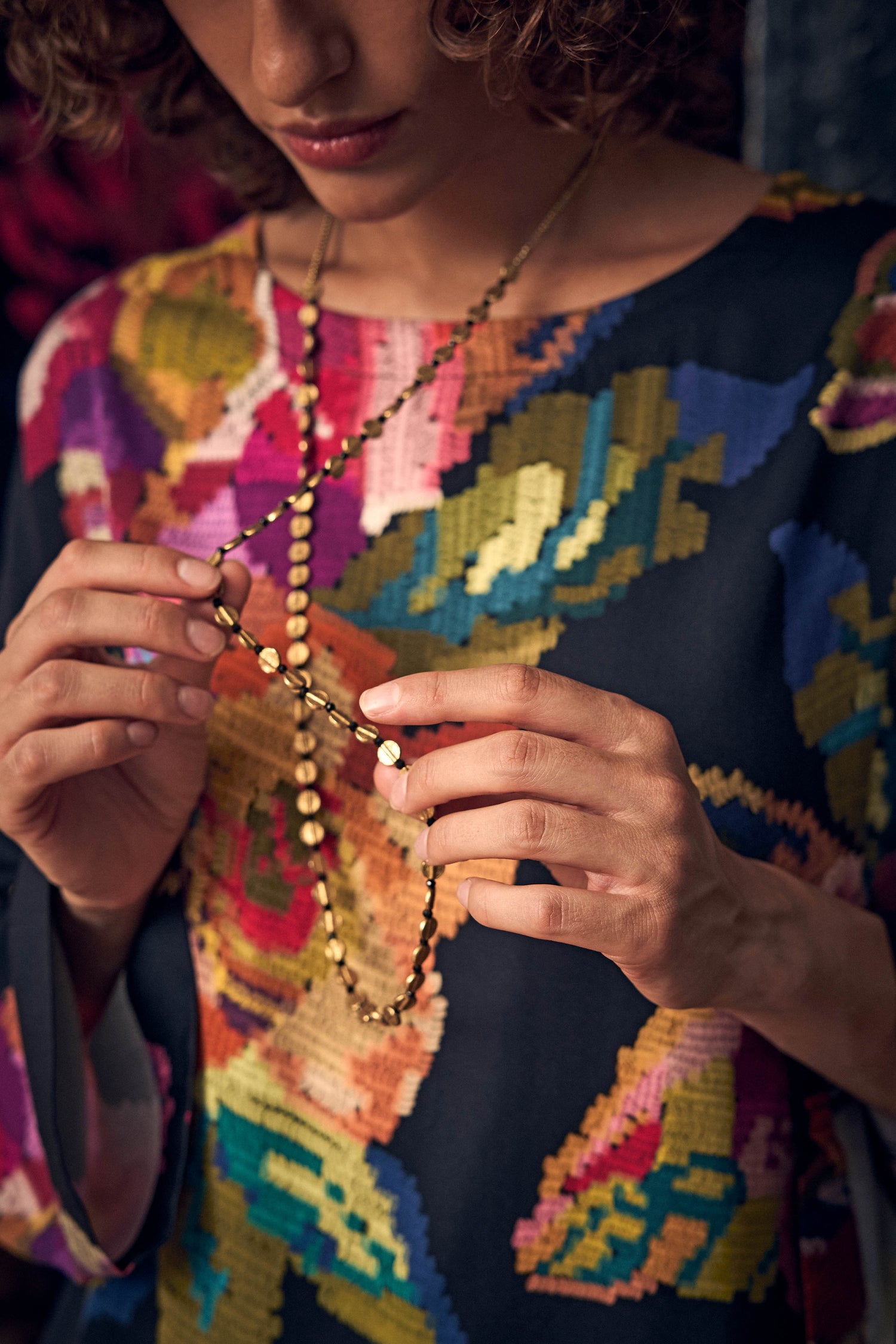 Person wearing a Mini Engraved Circles Bead Necklace, a long brass necklace featuring a series of small, flat, round discs.