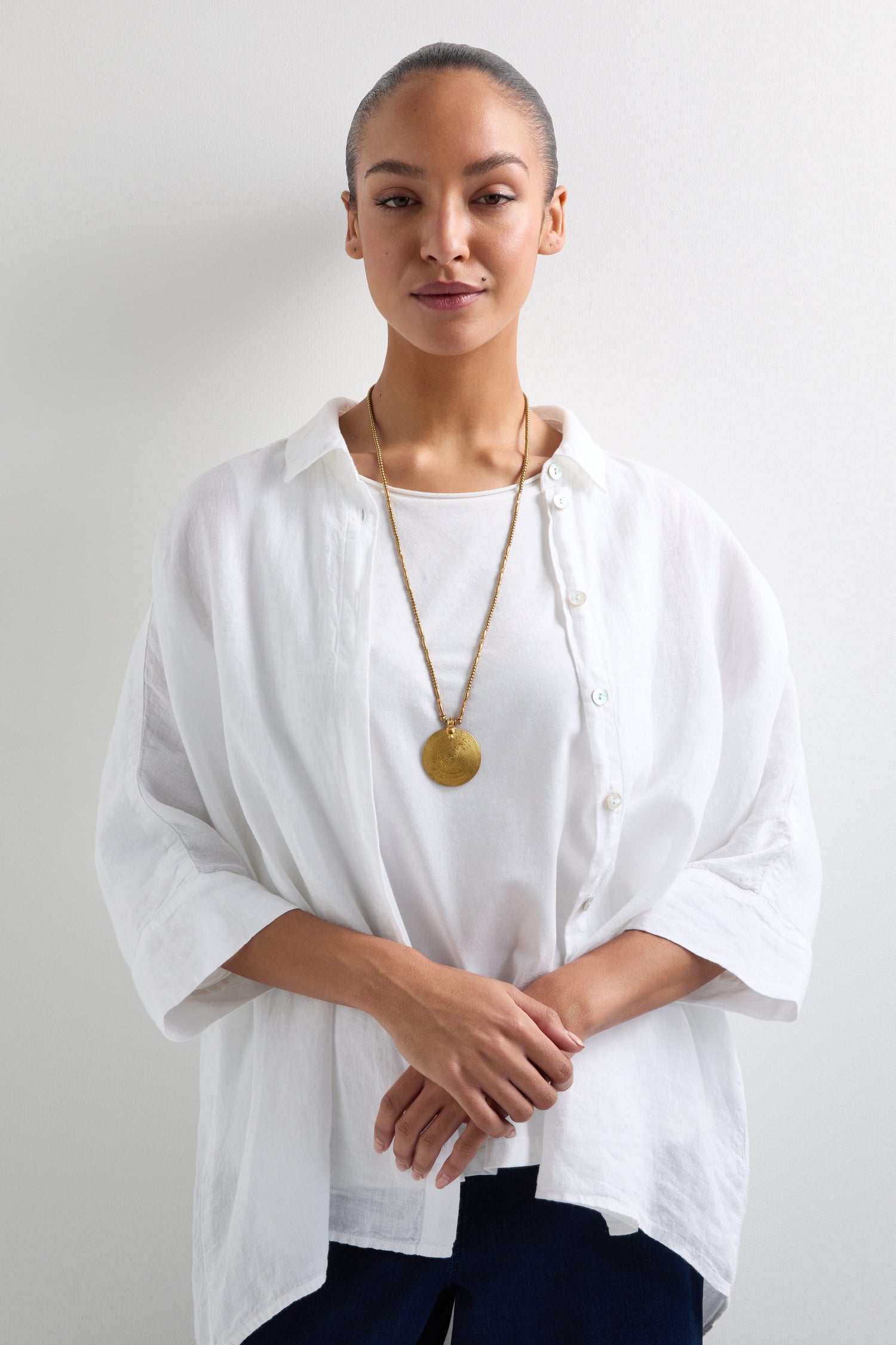 A woman in a white shirt and wearing a Long Spiral Pendant necklace stands against a plain background.