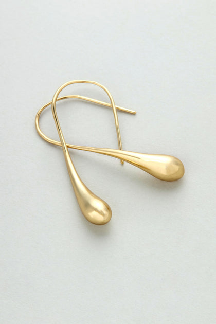 The Gilded Teardrop Earrings are handmade gold drop earrings with teardrop-shaped ends, showcased on a light, neutral background.