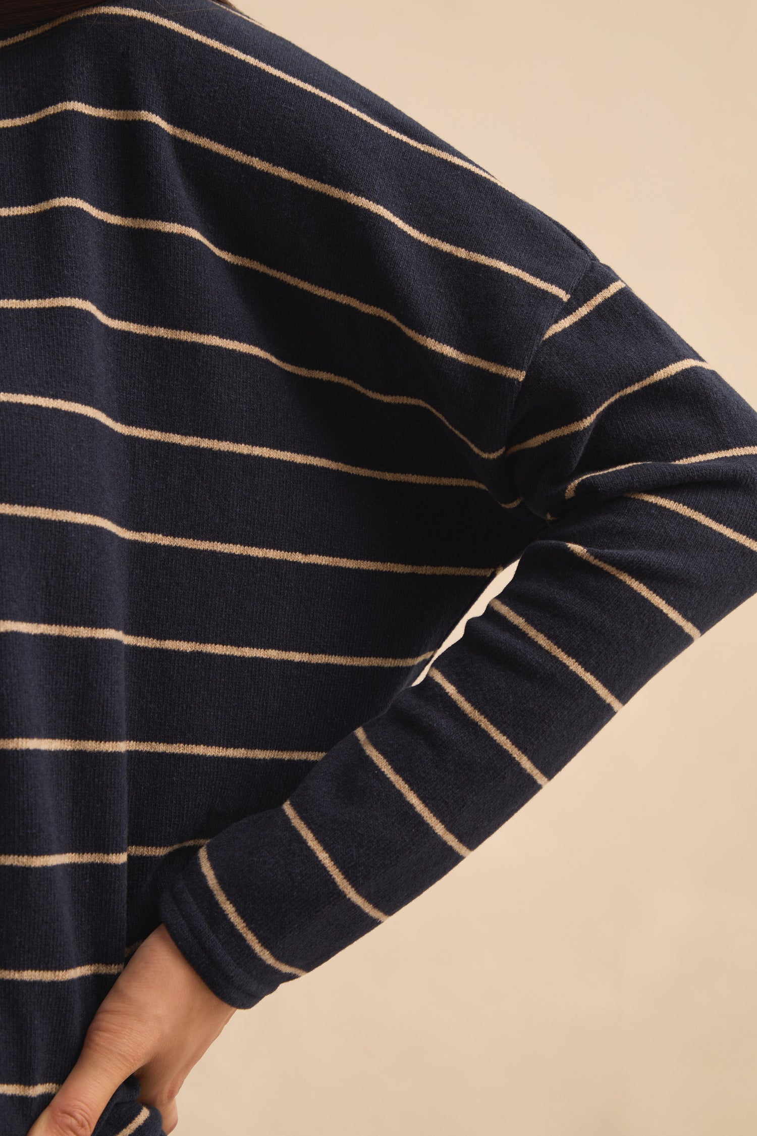Person wearing the Narrow Stripe Boxy Top in navy blue with thin white horizontal stripes, shown from the shoulders down with one hand on their hip. This boxy fit top is made in Italy and delivers effortless, sophisticated style.