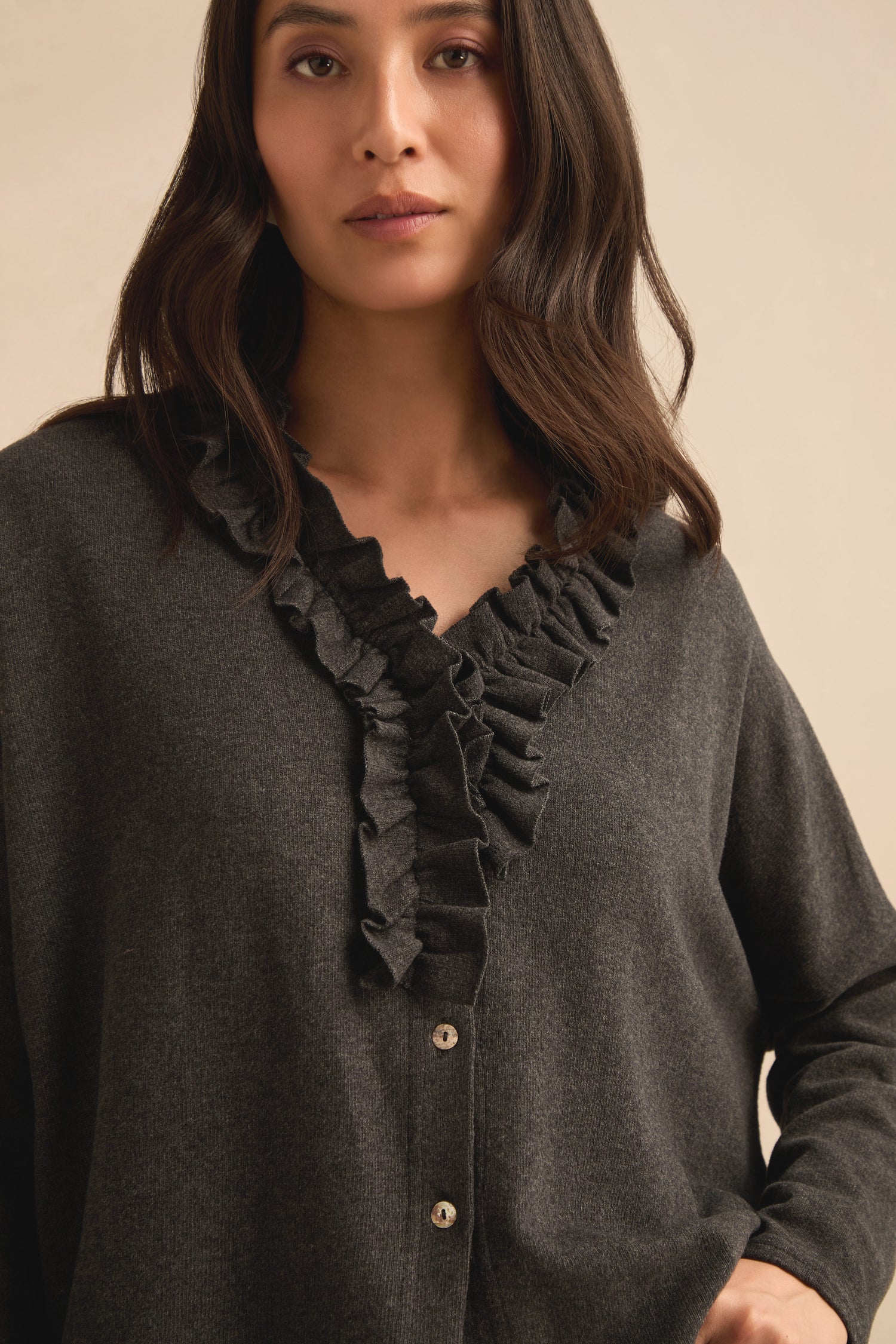 A woman wearing the Frill Neck Dark Grey Fleece Cardigan stands against a plain beige background.