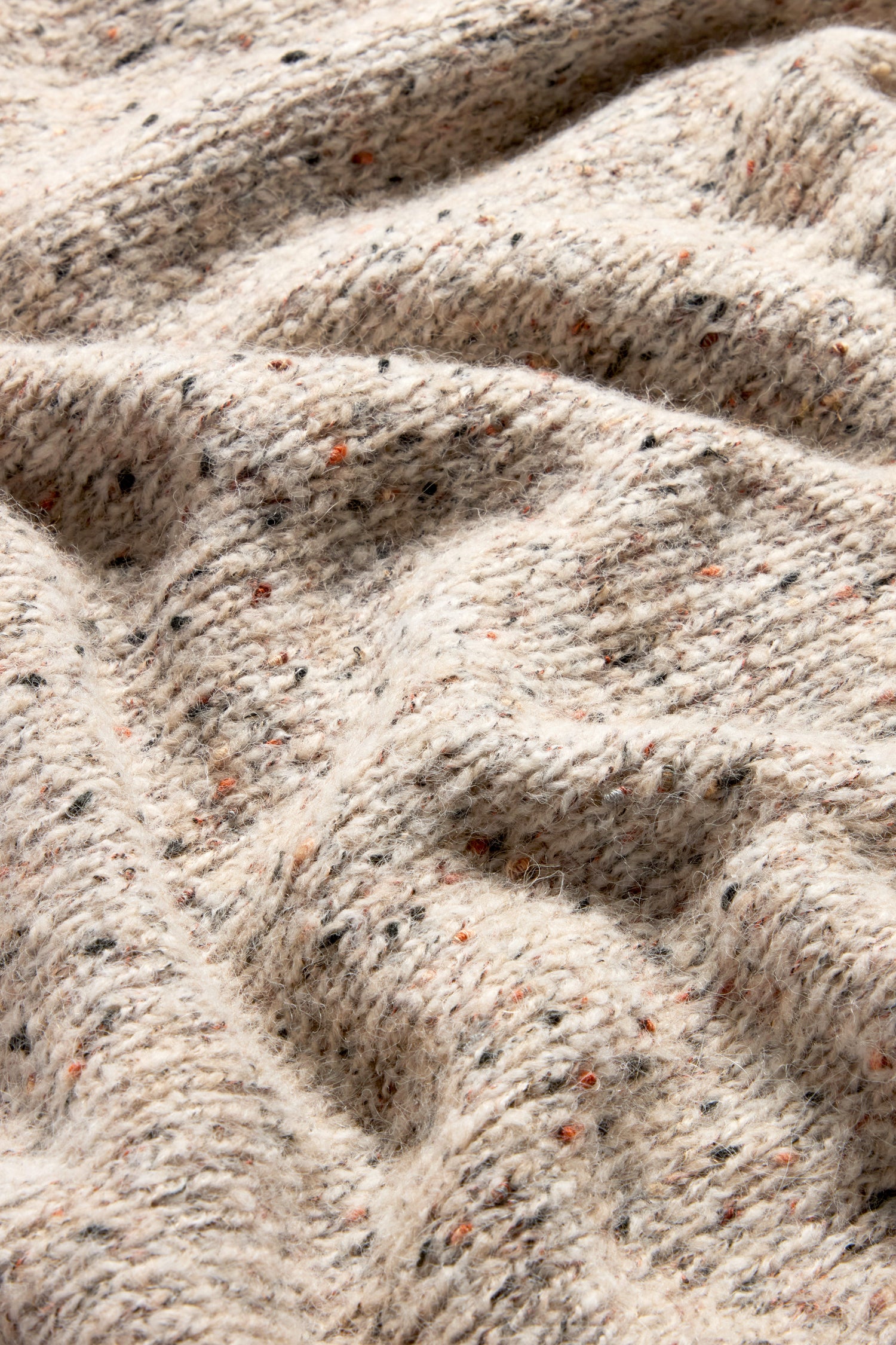 Close-up of beige, speckled fabric featuring a textured, woven pattern with varying colored flecks, reminiscent of the Marl Scoop Neck Knit's intricate knit designs.