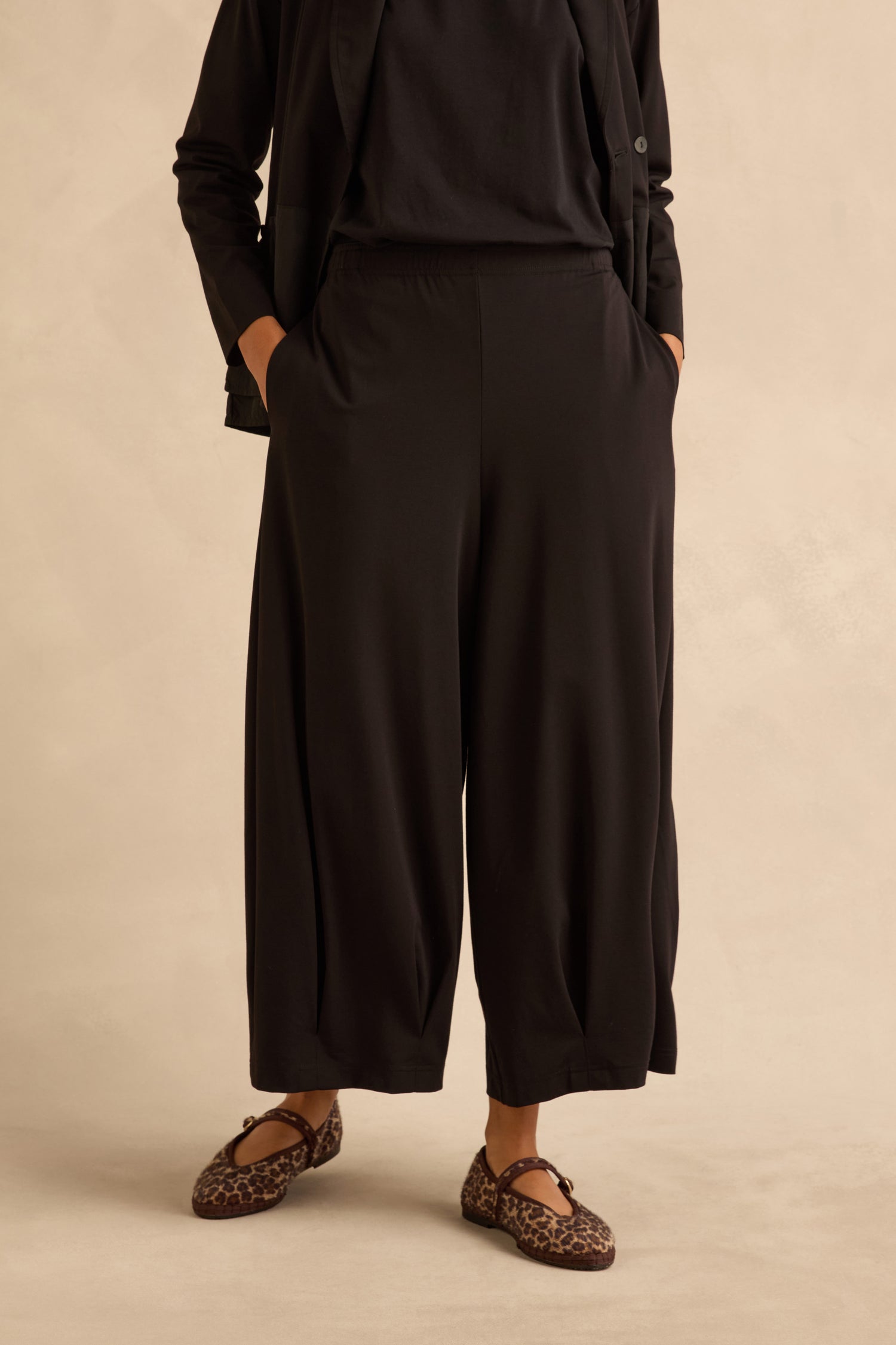 Black Pleated Hem Wide Jersey Trousers with side pockets, worn with leopard-print flats.