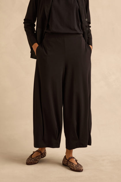 Black Pleated Hem Wide Jersey Trousers with side pockets, worn with leopard-print flats.