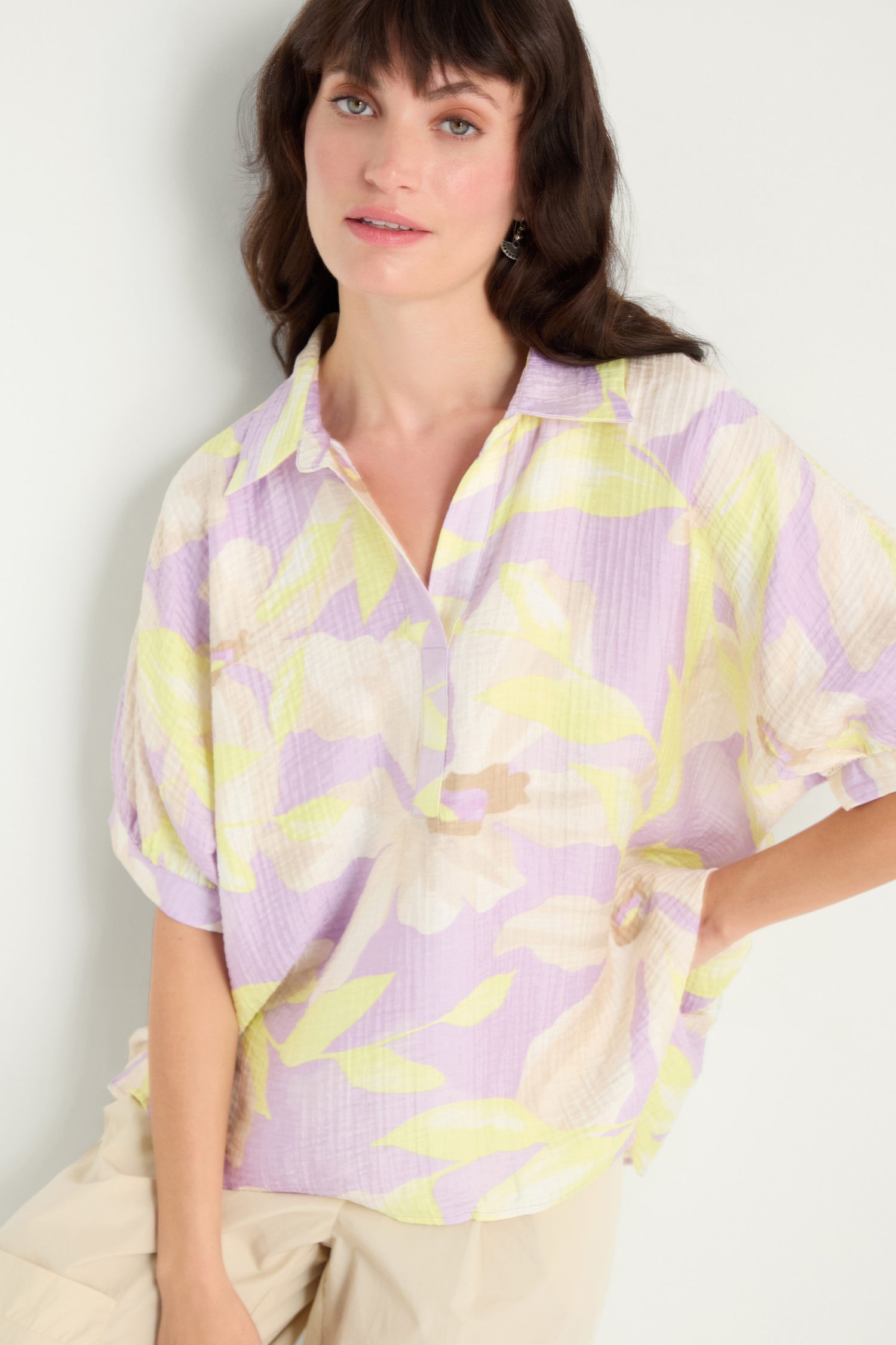 A woman models the Print Collar Top, a relaxed fit blouse with pastel floral print and short sleeves, paired with beige pants against a plain light background.