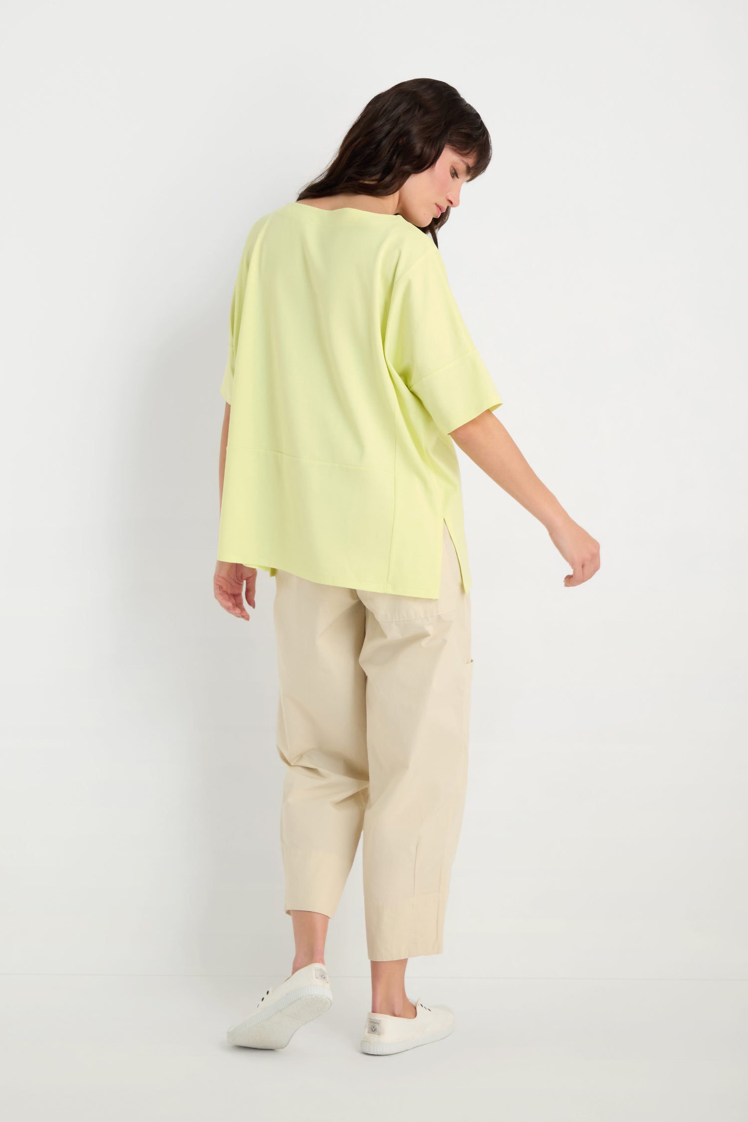 Person facing away against a white background, wearing the Jersey Pocket Top in light yellow—an easy-fit viscose jersey—paired with beige wide-leg pants and white sneakers.