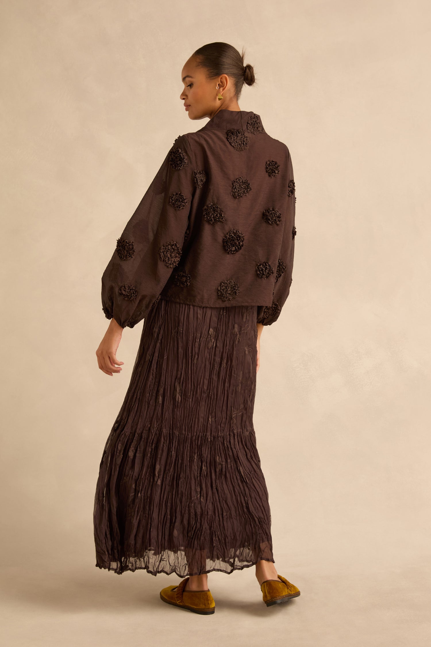 A person wearing an Applique Flowers Sheer Boxy Top with balloon sleeves and dark floral appliqués, paired with a matching floor-length tiered skirt.