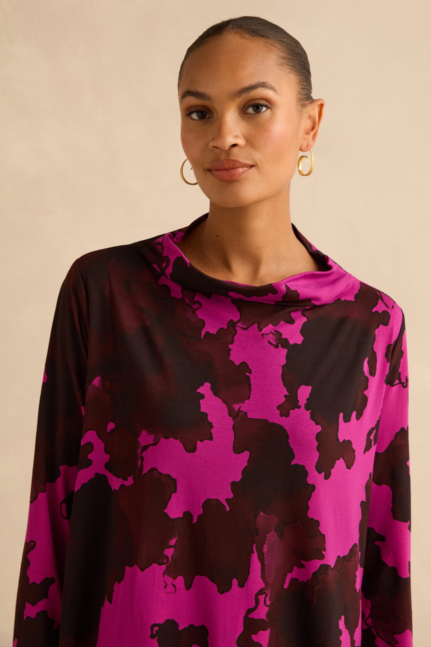A person wearing an Autumn Leaves Tunic in a stretch jersey fabric with a cowl neck and a dark purple and black abstract botanical print.