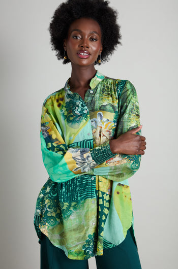 A person wearing a Patchwork Print Viscose Shirt with a stand collar and green pants stands confidently with arms crossed against a plain background.