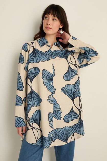 A woman wears the Ginkgo Viscose Linen Shirt in beige, featuring a relaxed silhouette, paired with blue jeans and standing against a plain light background.