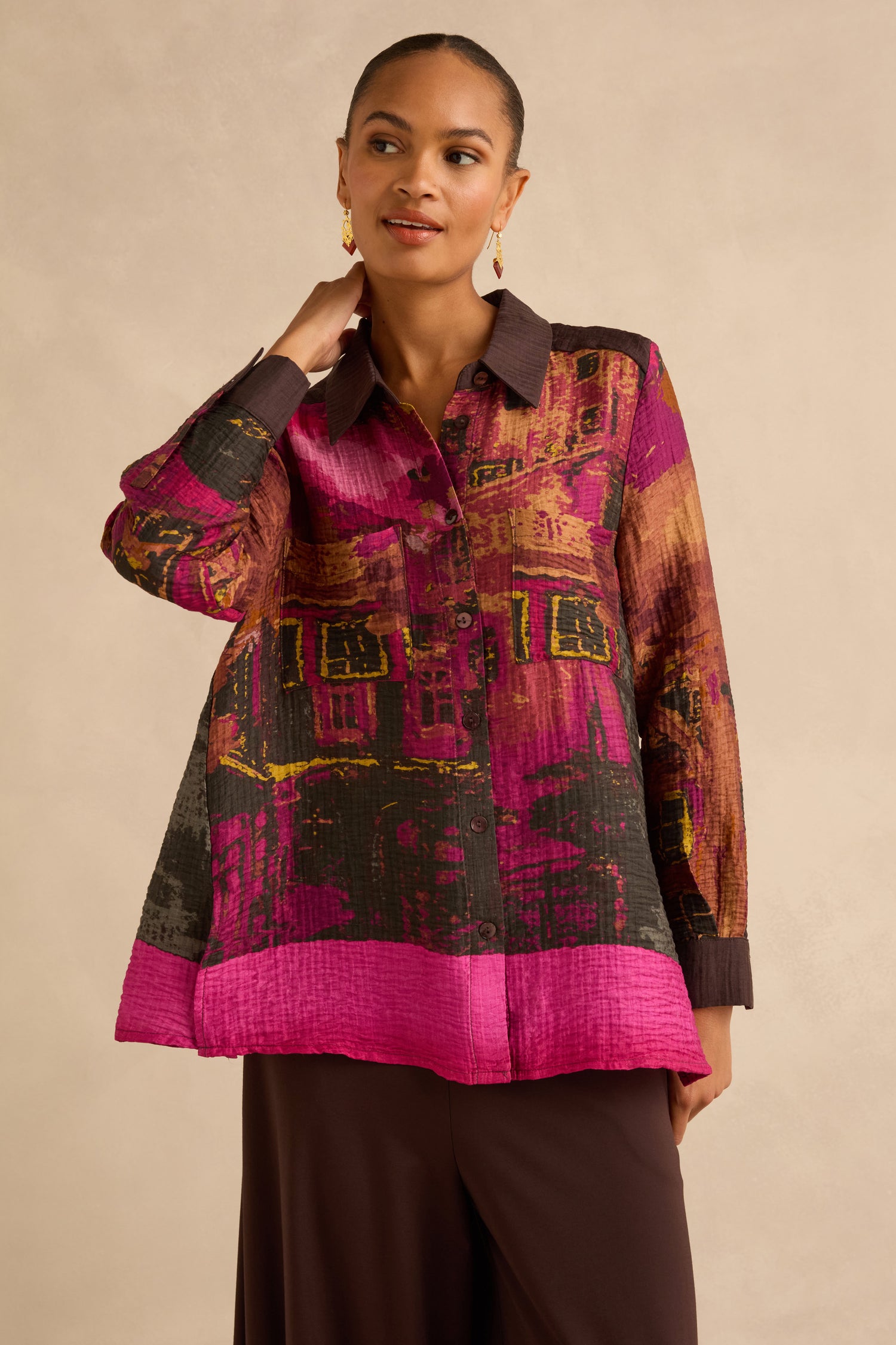 A person wearing a Window Print Pleated Shirt, featuring a long-sleeved, button-up design with a vibrant, abstract architectural print and a pleated texture.