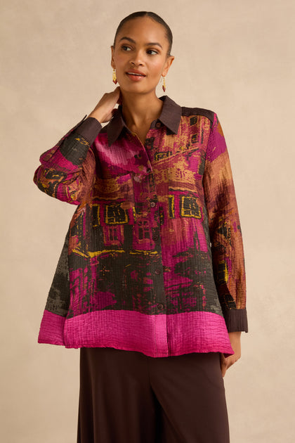 A person wearing a Window Print Pleated Shirt, featuring a long-sleeved, button-up design with a vibrant, abstract architectural print and a pleated texture.