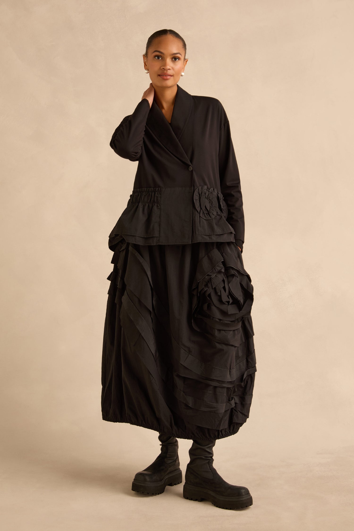 A person wearing a Taffeta Frill Hem Jacket with a gathered waist and a voluminous, layered midi skirt with a taffeta frill hem, paired with black boots.