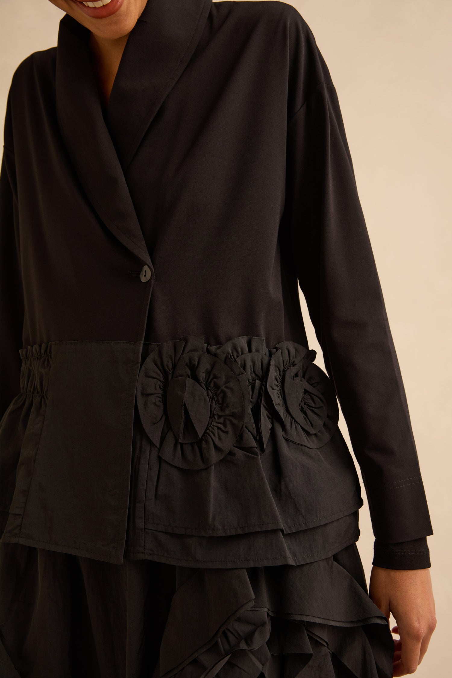 Taffeta Frill Hem Jacket: a black shawl collar blazer with a single button closure, gathered waist, and ruffled floral appliqué at the hip.