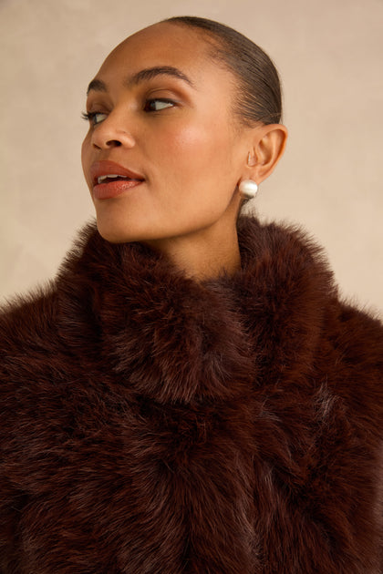 Close-up of a person wearing a dark brown Faux Fur Jacket with a high stand collar.